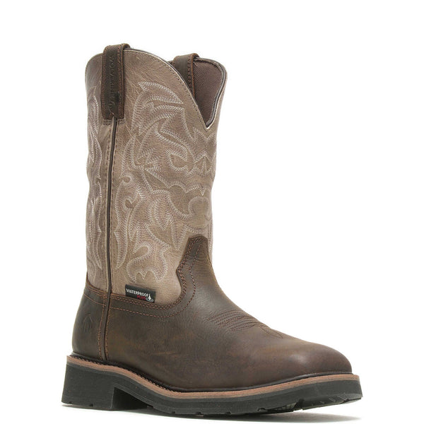 A brown waterproof steel-toe work wellington boot with a rubber lug outsole and detailed embossing on the upper shaft.