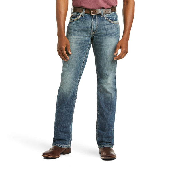 front view of person wearing medium wash distressed denim jeans with brown belt and boots