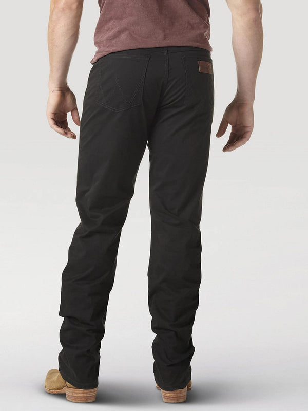 back view of man wearing black denim jeans with brown boots and hands by his sides