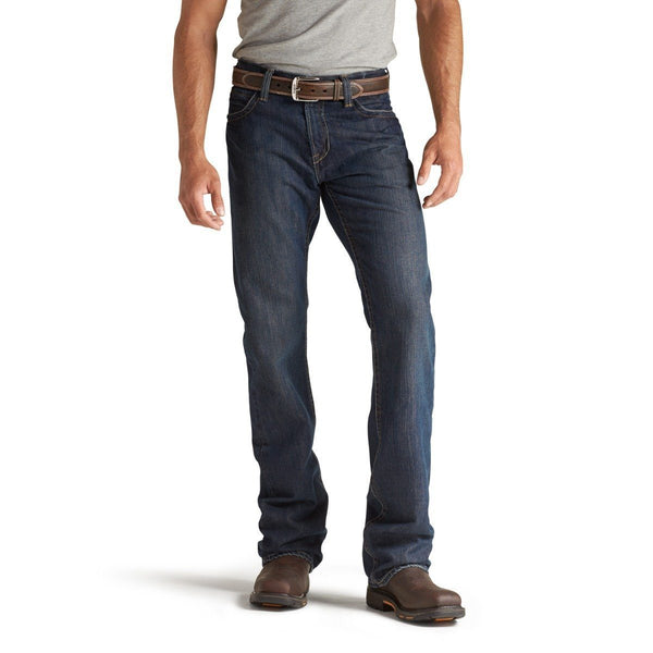 man wearing grey shirt tucked into dark blue jeans wearing brown work boots