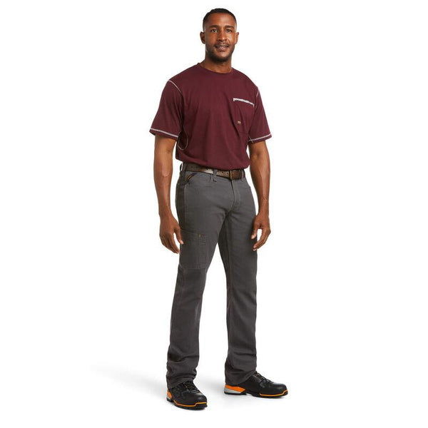 man wearing grey work pants and black and orange work shoes and purple shirt