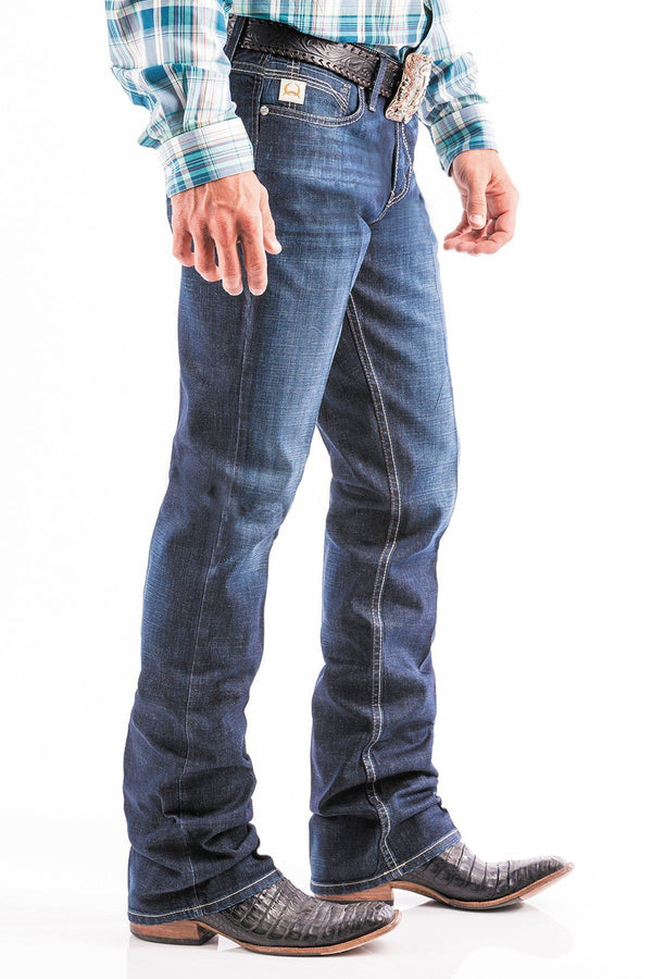 side view of man wearing blue jeans with large silver belt buckle and boots