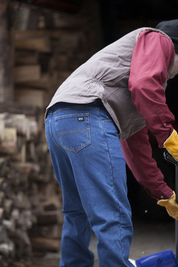 man wearing blue denim boot cut jeans and brown vest