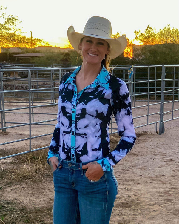 woman outside wearing black and white tie dye long sleeve button up shirt with turquoise accents and white cowgirl hat
