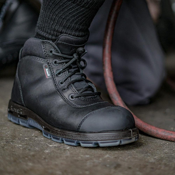 foot wearing black work boot with black string and black eyelets