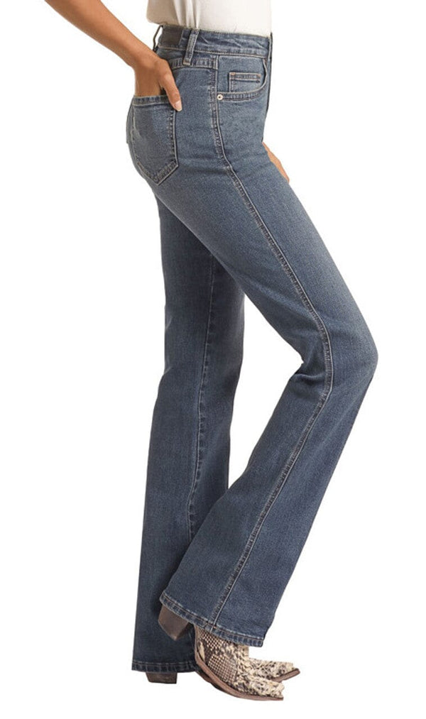 side view of woman wearing medium blue button closure denim jeans, with cream top tucked in, and cream snake print boots