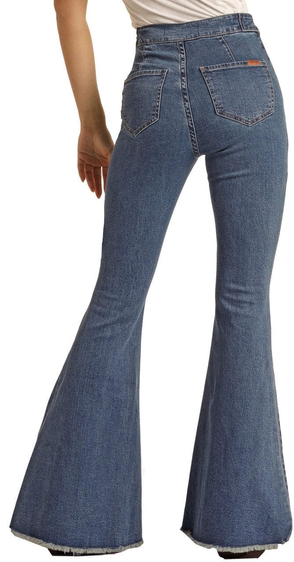 back view of woman wearing medium blue bell bottom jeans, with button details on waistband
