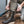 Load image into Gallery viewer, person kneeling one knee on wet concrete wearing dark brown high top moccasin style boots and holding yellow/brown laces