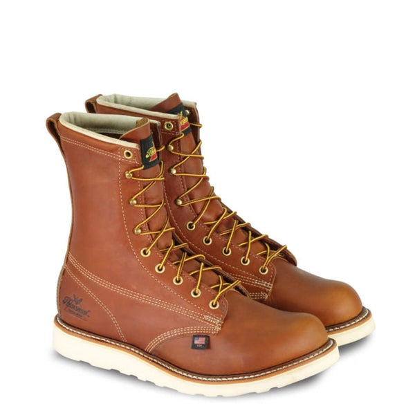 pair of mens brown logger boot with white interior, sticthing, and sole. Black thorogood logo stamped on heel with gold/red laces.