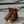 Load image into Gallery viewer, pair of worn-looking mens brown logger boot on concrete surface, with white interior and muddy sole. Brown/gold laces half unlaced.