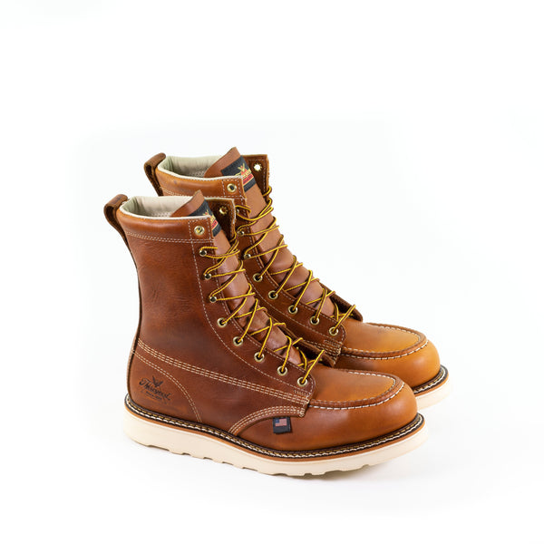 pair of mens brown logger boot with white interior, stitching, and sole, and brown/gold laces. Black thorogood logo stamped on heel.