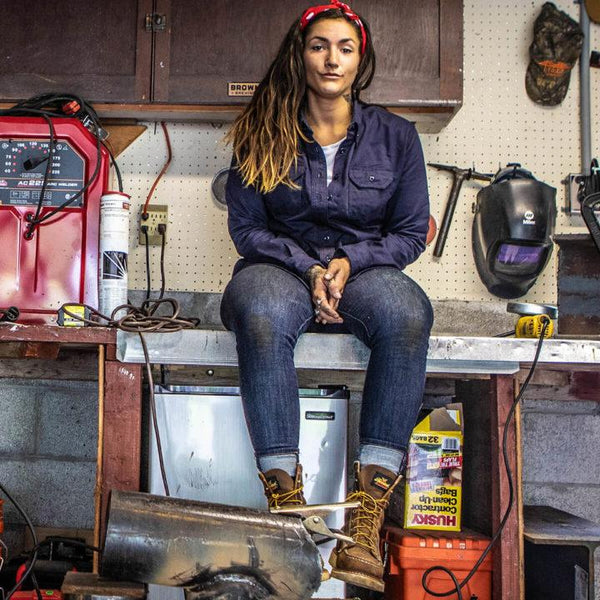 woman sitting on bench while wearing dark brown moccasin style boot with yellow and brown laces and white sole