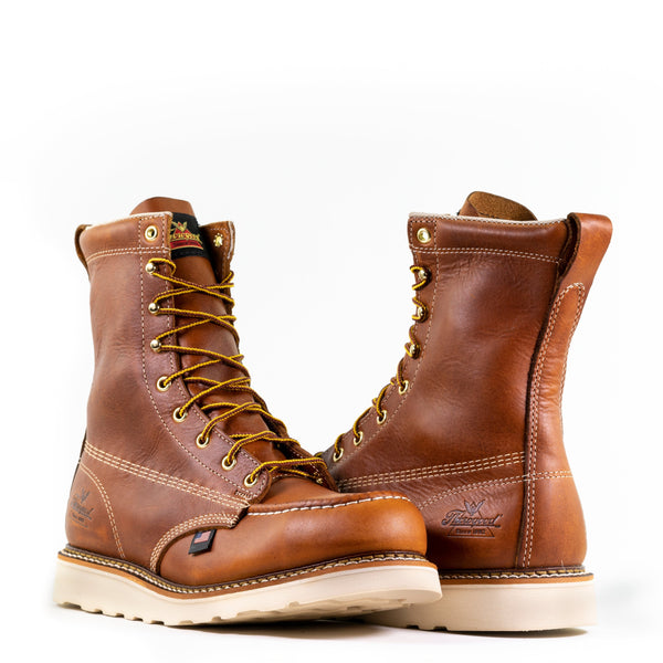 alternating pair of mens light brown logger boots with white sole, stitching and interior. Black Thorogood logo stamped on heel. Yellow laces.