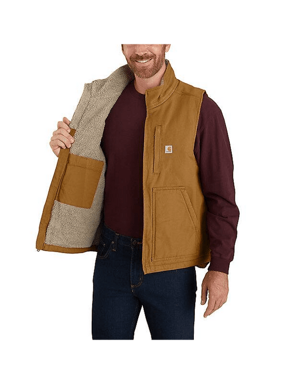 man holding tan Carhartt vest open over red long sleeve shirt
