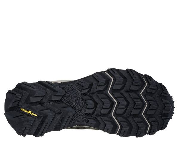 Bottom black sole of trail shoe with all-terrain zig zag tread pattern and Good Year logo in yellow.