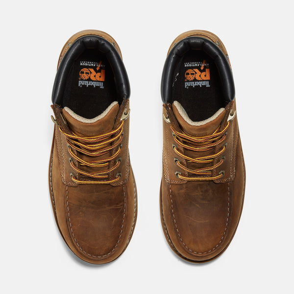 Top view of pair of brown leather boots with yellow laces on a white background
