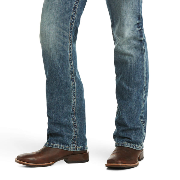 close up view of distressed denim medium wash jean pant legs and brown boots