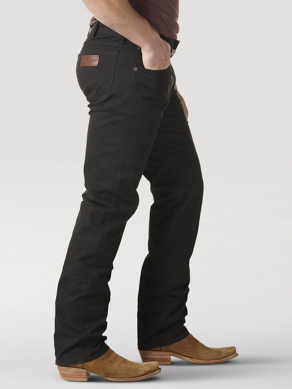 side view of man wearing black denim jeans with brown boots and right hand in front pocket