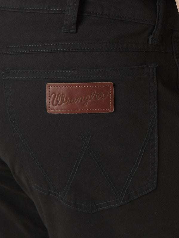 Detailed close view of black denim jeans back pocket with sewn on Wrangler patch
