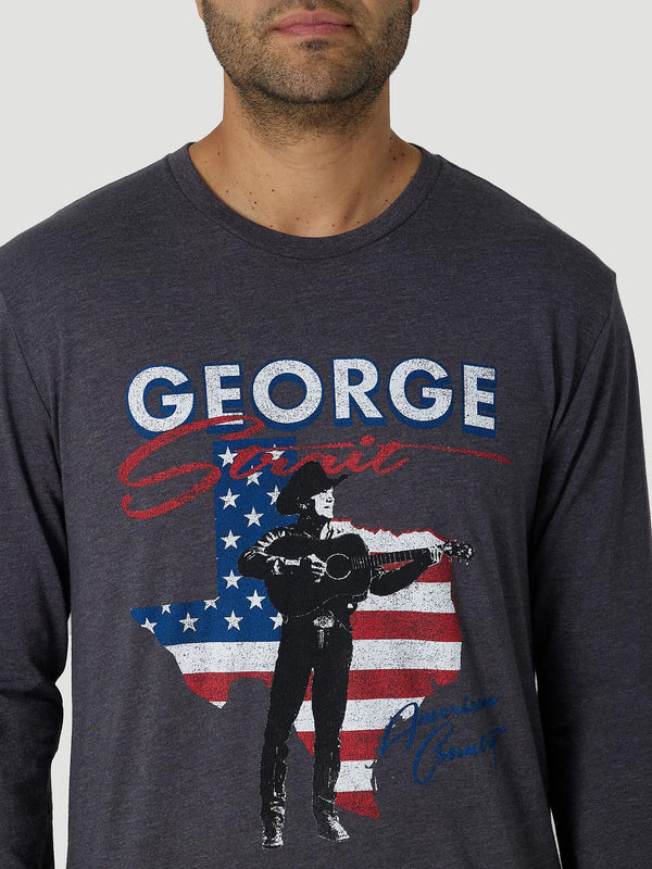close up of man wearing dark grey long sleeve shirt with image of George Strait silhouette strumming his guitar over a red, white, and blue American flag outline of Texas