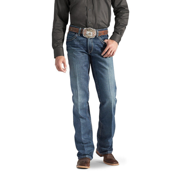 Man wearing a dark grey button up tucked into faded wash blue jeans with a gold belt buckle and cowboy boots