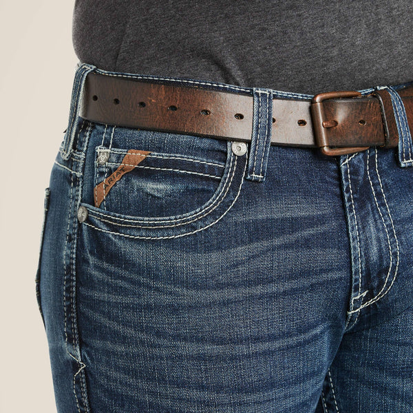 front pocket close up view of man wearing blue jeans with white stitching and a charcoal shirt and brown belt