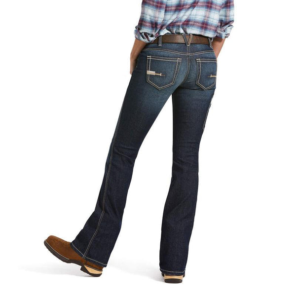 back view of woman from chest down wearing red and blue plaid and dark blue jeans