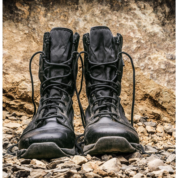 two black high top boots on top of rocks