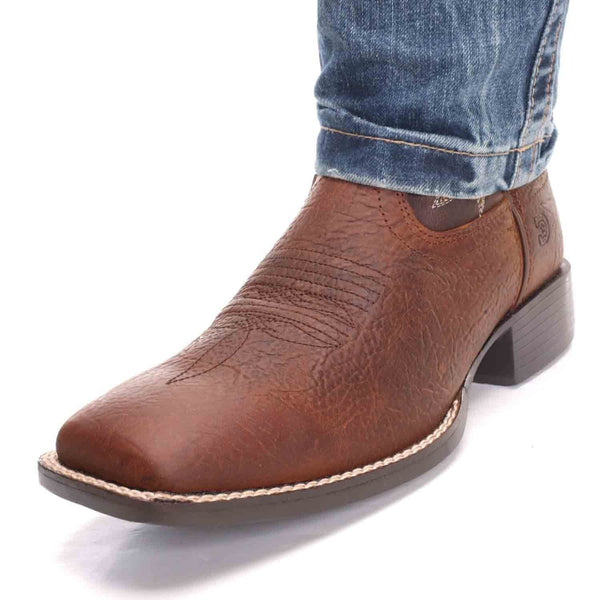 angled view of square toe distressed brown vamp cowboy boot with light blue jeans over shaft