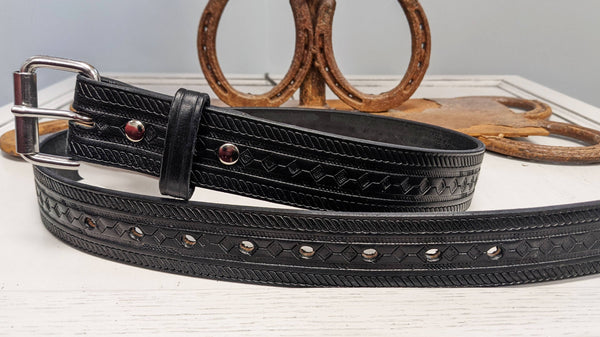 black leather belt with stamped design on table