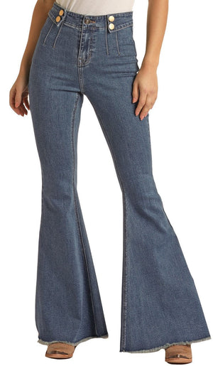 woman wearing medium blue bell bottom jeans, with button details on waistband and tan point toe boots