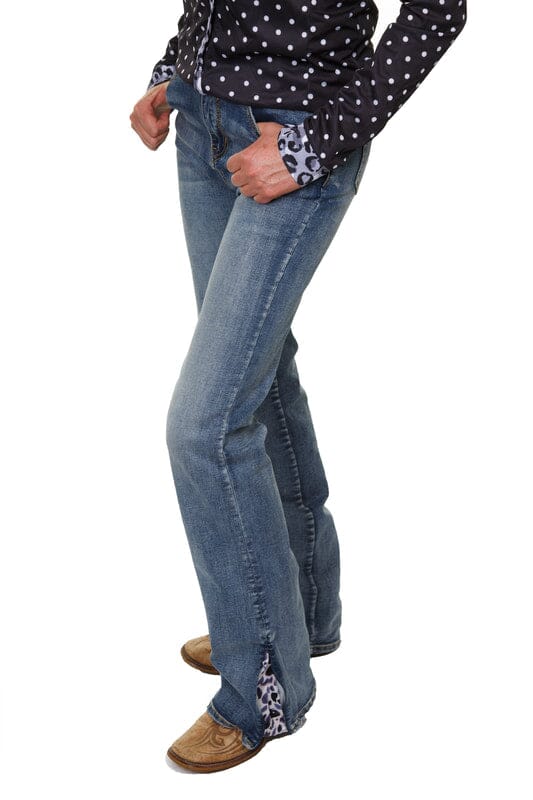 woman wearing blue jeans with leopard print vented hem and black polka dot shirt with thumbs in front pockets