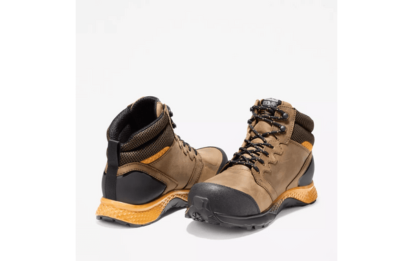 pair of mens light brown logger boot with yellow and black soles. Black toe, heel, and laces.