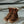 Load image into Gallery viewer, pair of worn-looking mens brown logger boot on concrete surface, with white interior and muddy sole. Brown/gold laces half unlaced.
