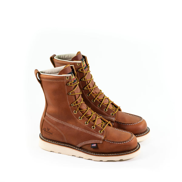 Pair of mens light brown logger boots with white sole, stitching and interior. Yellow laces.