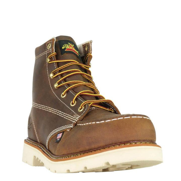 Front angled view of mens six inch brown logger boot with cream interior, sticthing, and sole. Thorogood logo stamped on heel with gold/red laces.