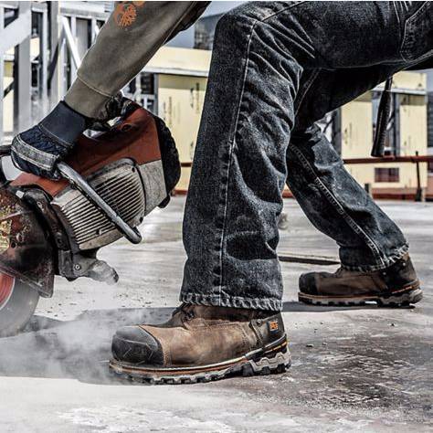 man working with power tools wearing dark jeans and timberland boots