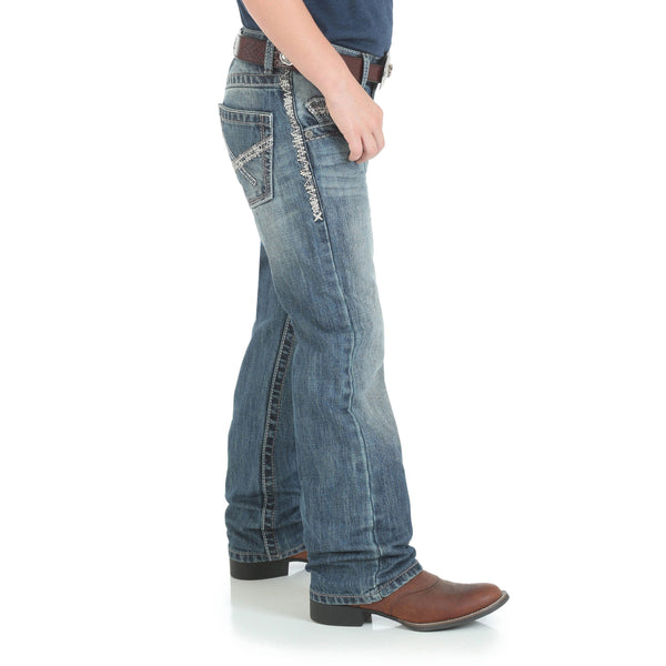boy in navy shirt and big brown belt with faded jeans side view